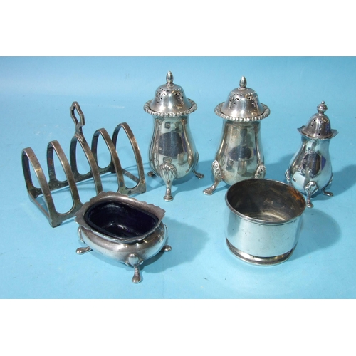 518 - A pair of pepper casters on three shell feet, other cruet items and a four-division toast rack, weig... 