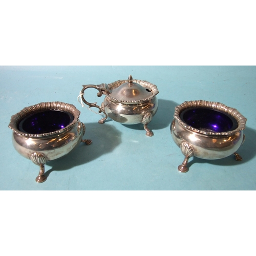 515 - A three-piece Georgian-style cruet set, mustard and two salts, of cauldron form, on three feet, with... 