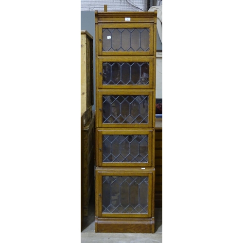 10 - A Minty oak bookcase, having seven leaded glazed small doors, 134cm wide, 117cm high, (some damage t... 