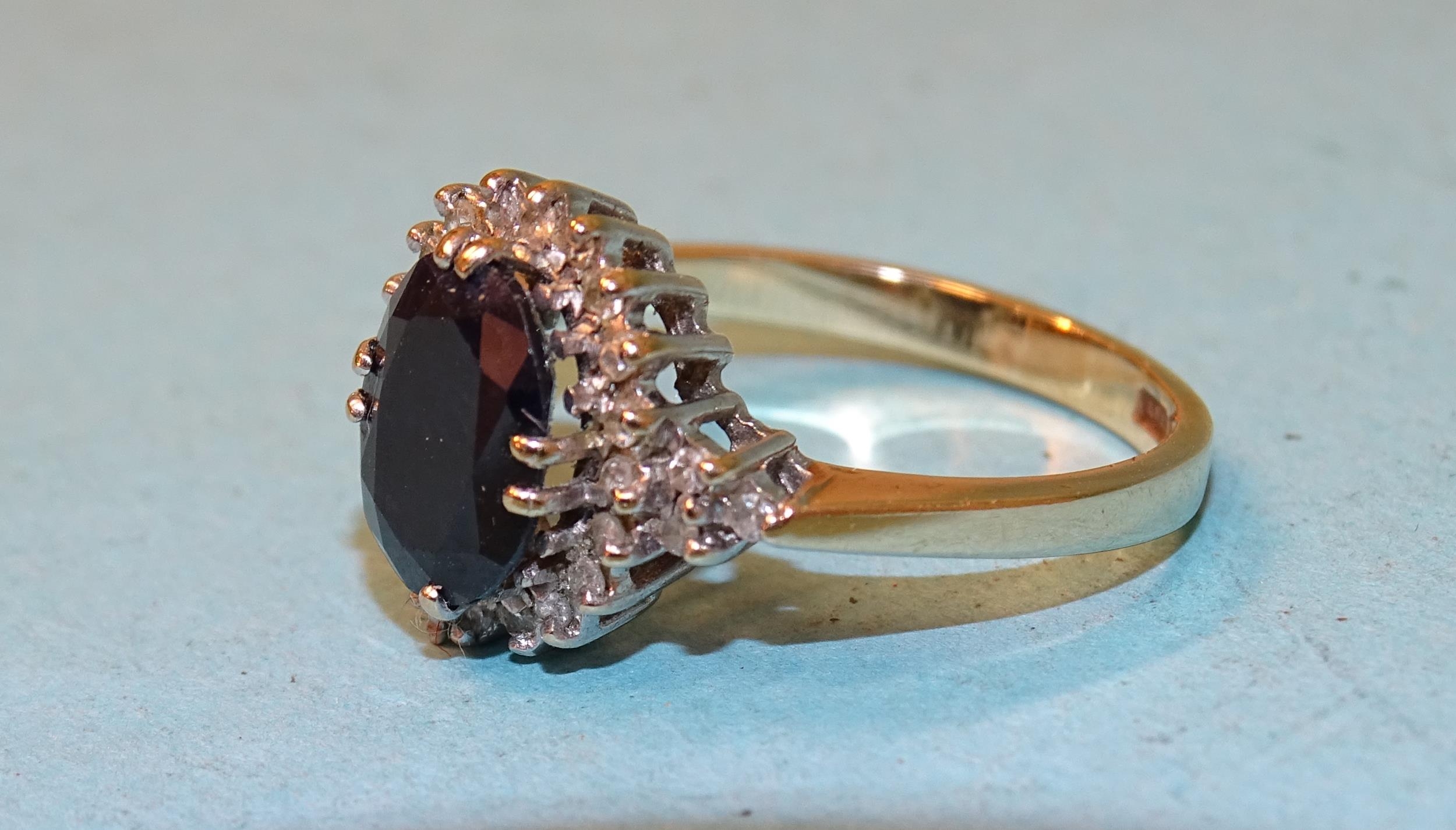 A sapphire and diamond cluster ring claw-set an oval sapphire within a ...