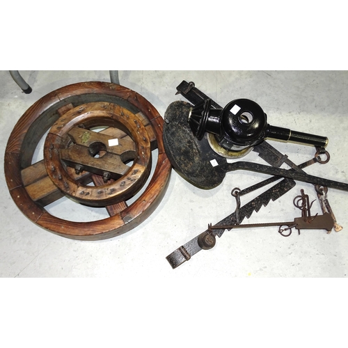 105 - Two iron pot hangers, a hanging balance scale and two French polished wood pulley wheels, one with m... 