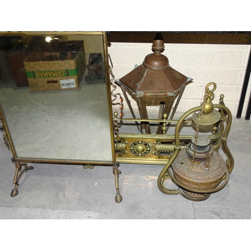 43 - A small brass fire surround, 83cm wide, a suspended brass oil lamp, a brass-framed mirrored fire scr... 
