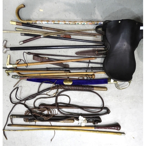 51 - A collection of various walking canes, riding crops, a small saddle marked Barrett (a/f) and other i... 