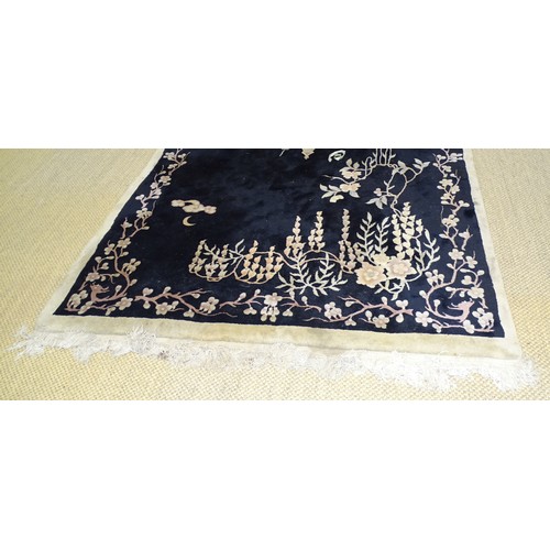 14 - A Chinese rug decorated with prunus on a black ground, 270 x 170cm.