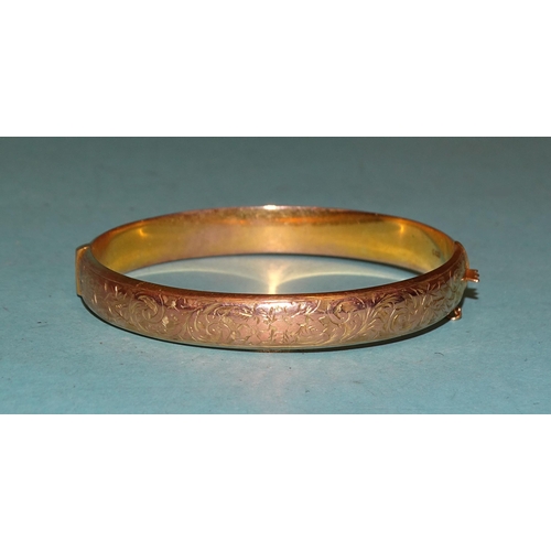 240 - A 9ct gold hinged bangle with engraved decoration, internal dimensions 6 x 5.3cm, 10g.... 