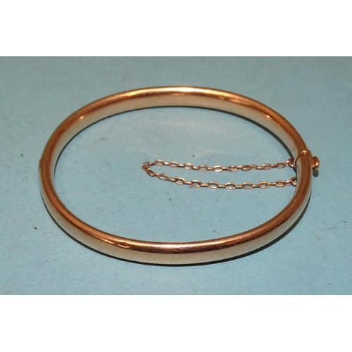 269 - A 15ct gold hinged bangle of plain form, interior measurements 5.7 x 5cm, 11.8g.