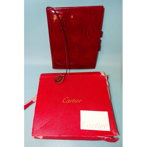 317 - Cartier, a leather notebook embossed with the Cartier emblem, (first page torn out), boxed with leaf... 