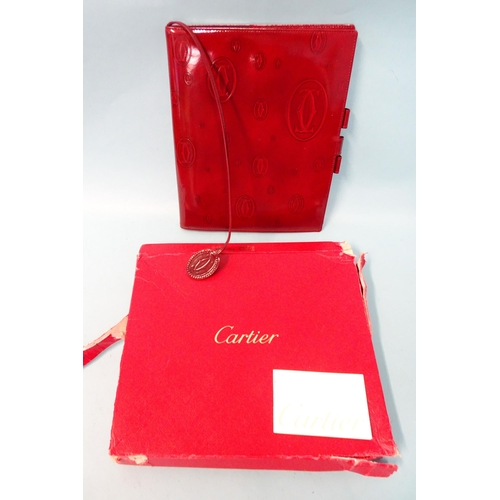 317 - Cartier, a leather notebook embossed with the Cartier emblem, (first page torn out), boxed with leaf... 