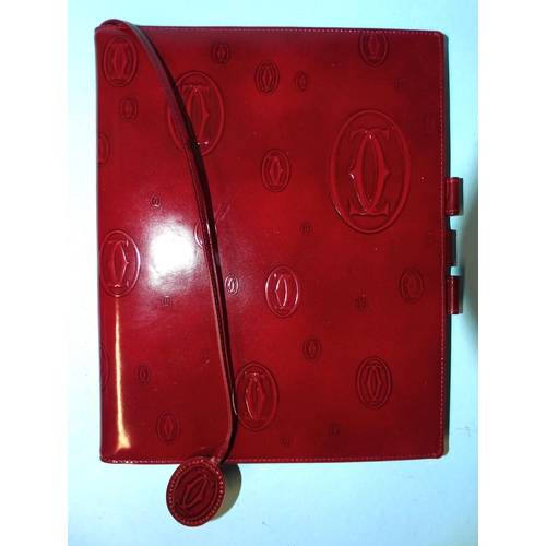 317 - Cartier, a leather notebook embossed with the Cartier emblem, (first page torn out), boxed with leaf... 