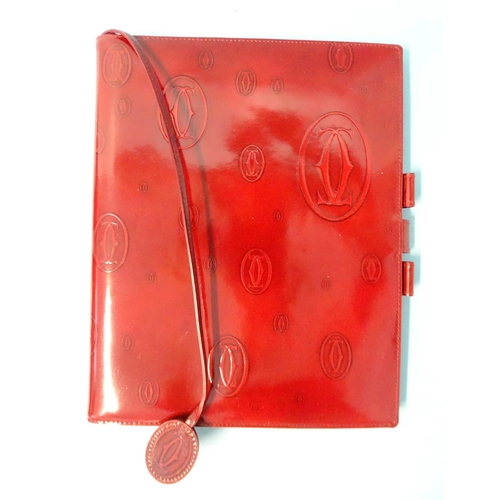 317 - Cartier, a leather notebook embossed with the Cartier emblem, (first page torn out), boxed with leaf... 