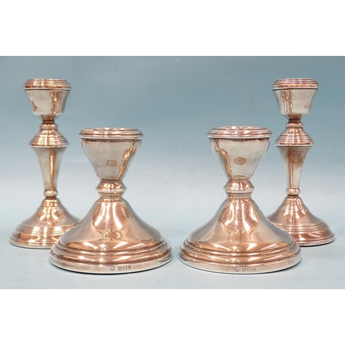 401 - A pair of short silver candlesticks with loaded bases, 10cm high, Birmingham 1960 and a later pair, ... 