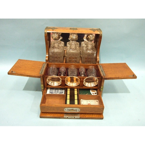 72 - A Victorian/Edwardian Tantalus and games compendium fitted with three decanters, original matching g... 