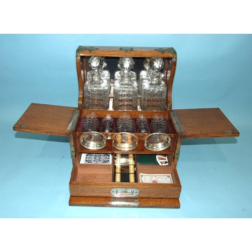 72 - A Victorian/Edwardian Tantalus and games compendium fitted with three decanters, original matching g... 