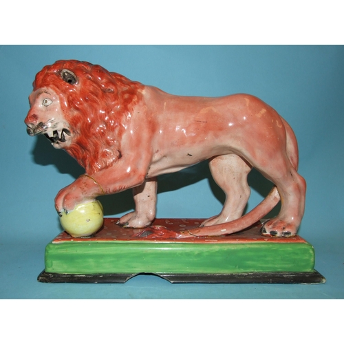 95 - An early Staffordshire model of a Medici lion, with left paw on a globe, on oblong plinth, 31cm long... 