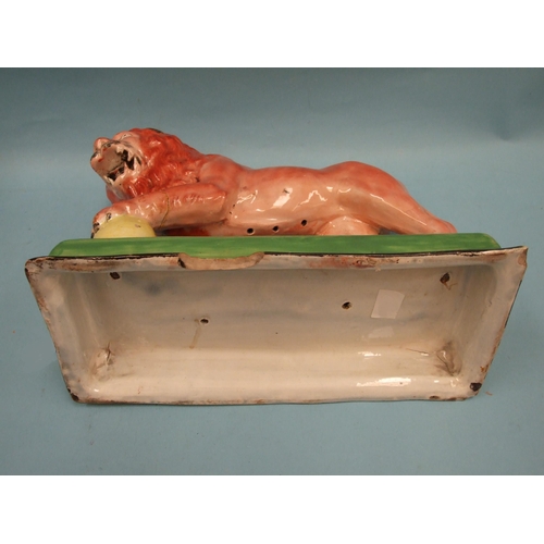 95 - An early Staffordshire model of a Medici lion, with left paw on a globe, on oblong plinth, 31cm long... 