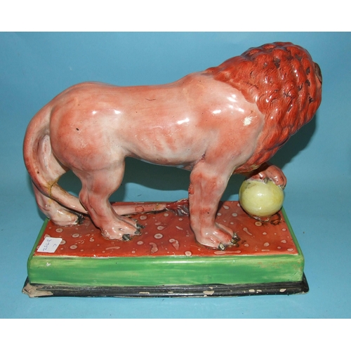 95 - An early Staffordshire model of a Medici lion, with left paw on a globe, on oblong plinth, 31cm long... 