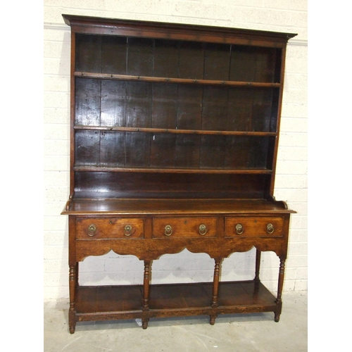 62 - An 18th century oak dresser with three-shelf plate rack, the base with three drawers, on turned supp... 