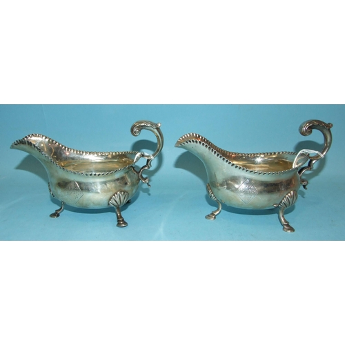 430 - A pair of George III silver sauce boats with gadrooned rims and scroll handles, on three shell suppo... 