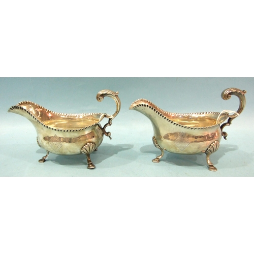 430 - A pair of George III silver sauce boats with gadrooned rims and scroll handles, on three shell suppo... 