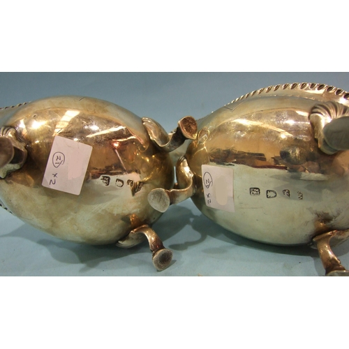 430 - A pair of George III silver sauce boats with gadrooned rims and scroll handles, on three shell suppo... 