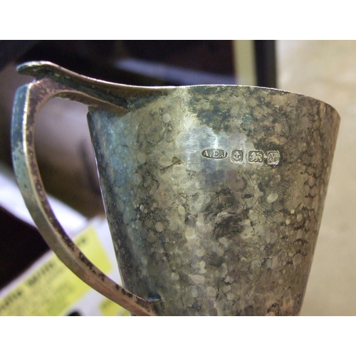 455 - An Arts & Crafts silver hammered mug on circular foot (dented), 8.5cm high, by Albert Edward Jon... 