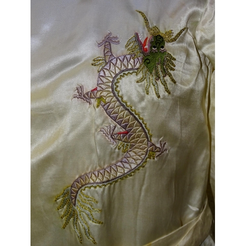 303 - A Chinese child's ivory silk robe with embroidered dragons.