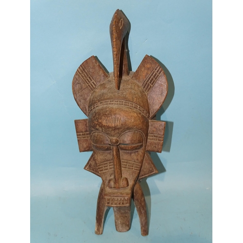 464 - A small carved wood African mask surmounted by a stylised bird headdress, 43cm, an African tribal bl... 