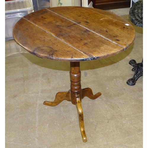 74 - A 19th century oak circular tilt-top table, on turned column and triform support, 73.5cm diameter.... 