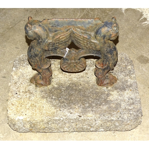 85 - A cast iron boot scrape with winged cats, set in concrete.