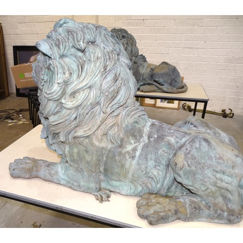 86 - An impressive and large pair of cast metal and coppered lions, each recumbent lion with open mouth, ... 