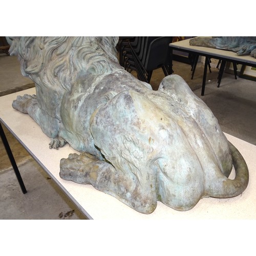 86 - An impressive and large pair of cast metal and coppered lions, each recumbent lion with open mouth, ... 