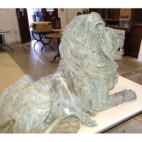 86 - An impressive and large pair of cast metal and coppered lions, each recumbent lion with open mouth, ... 