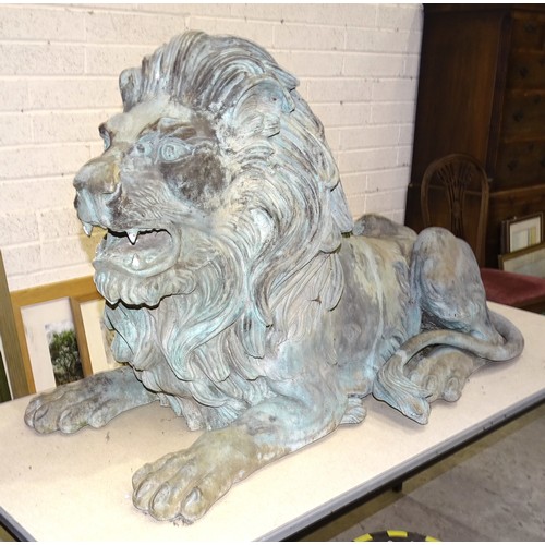 86 - An impressive and large pair of cast metal and coppered lions, each recumbent lion with open mouth, ... 