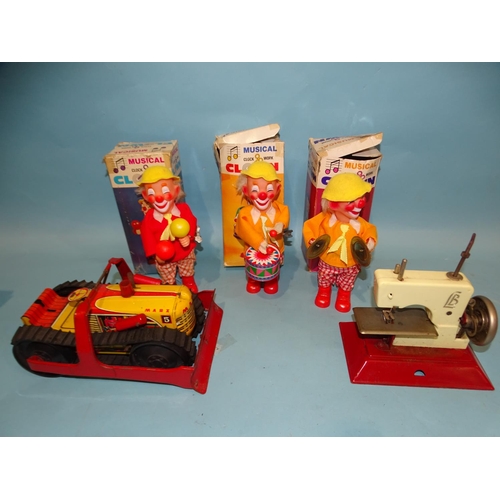 99 - Three boxed musical clockwork clowns, a Marx 5 tinplate bulldozer and an LB toy sewing machine,... 