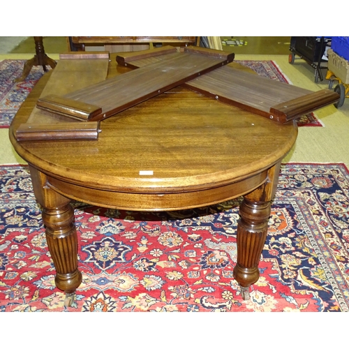 3 - An Edwardian mahogany extending dining table with rounded ends and three spare leaves, on turned ree... 