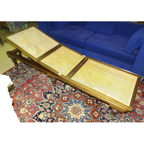 11 - A 19th century mahogany-framed day bed, the hinged caned seat on turned legs with castors, 200 x 60c... 