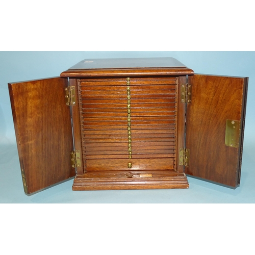 212 - A mahogany coin collectors cabinet fitted with a pair of hinged doors with inlaid vase decoration op... 