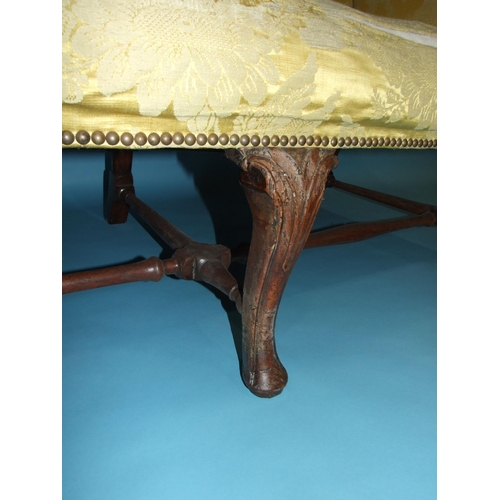 18 - *An 18th century three-seat settee of upholstered back, seat and scroll arms, on three carved front ... 