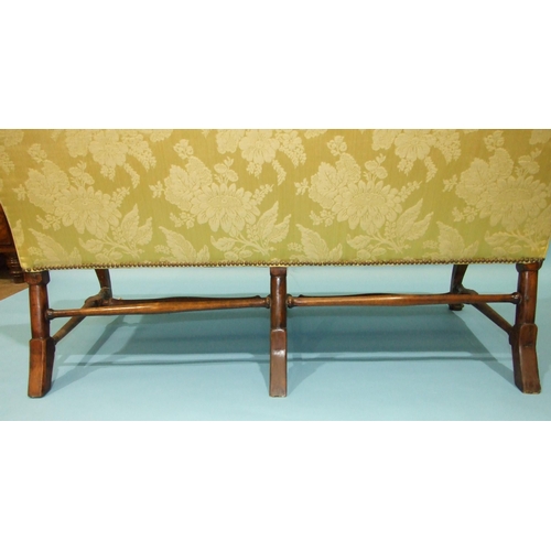 18 - *An 18th century three-seat settee of upholstered back, seat and scroll arms, on three carved front ... 