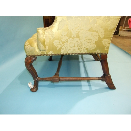 18 - *An 18th century three-seat settee of upholstered back, seat and scroll arms, on three carved front ... 