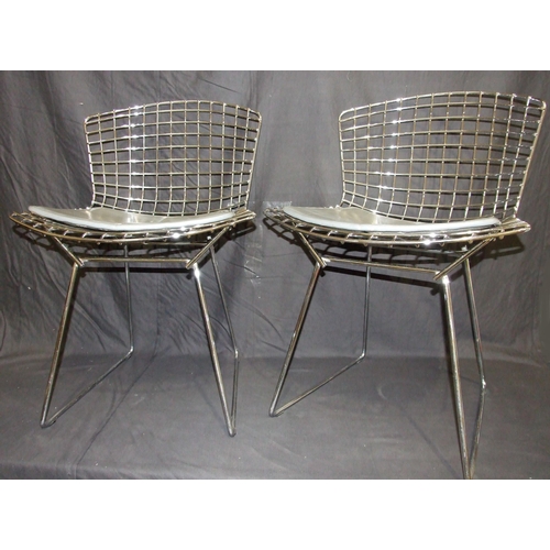 27 - A pair of side chairs designed by Harry Bertoia, the chrome plated frames with grey leather seat pad... 