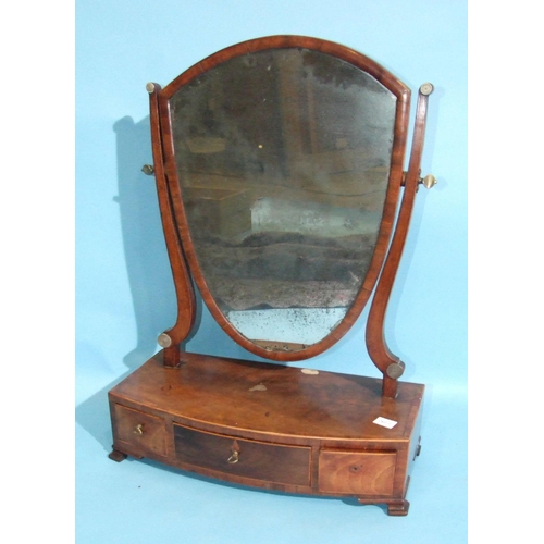 6 - A Georgian mahogany dressing glass, the shield-shaped mirror above a crossbanded bow-front base fitt... 