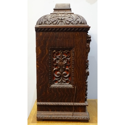 94 - An early-20th century musical bracket clock, the heavily-carved oak domed case with arched door and ... 