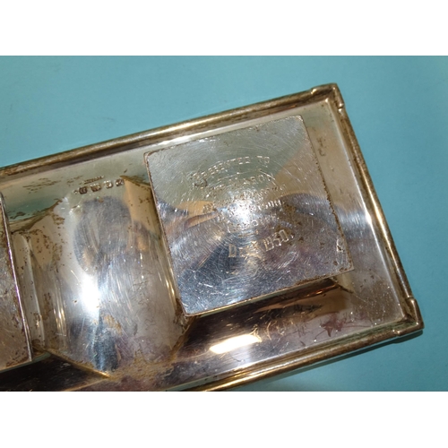 512 - A George V silver inkstand of rectangular form, on loaded base, fitted with two hinged lidded inkwel... 