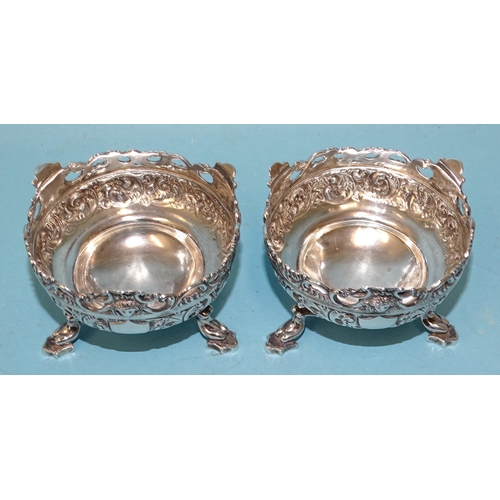 533 - A pair of late-Victorian silver salts with embossed and pierced scroll decoration, raised on three w... 