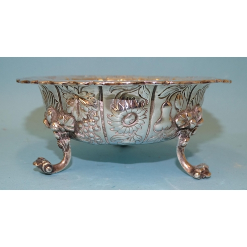 546 - A William IV silver bowl of lobed form embossed with fruit and flowers, raised on three scroll legs,... 