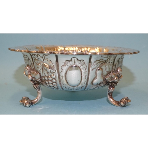 546 - A William IV silver bowl of lobed form embossed with fruit and flowers, raised on three scroll legs,... 