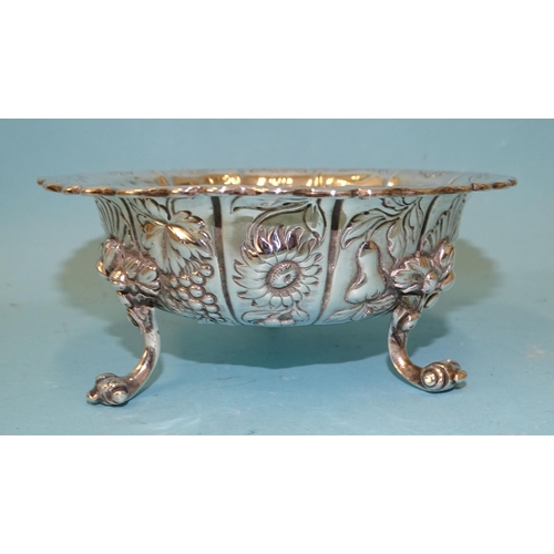 546 - A William IV silver bowl of lobed form embossed with fruit and flowers, raised on three scroll legs,... 