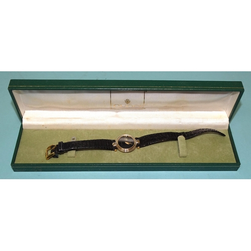 687 - Gucci, a lady's gold-plated wrist watch with black dial and quartz movement, on leather strap, (in o... 