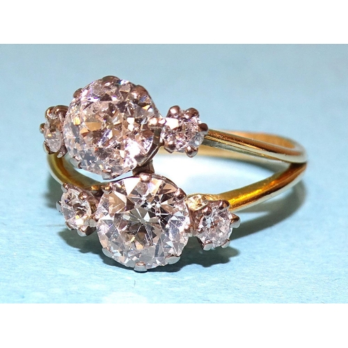 A diamond ring asymmetrically-claw-set two old brilliant-cut diamonds, one approximately 1.29cts, the other 1.44cts, each with a smaller brilliant-cut diamond to either side, colour F-G approximately, clarity VS2, in 18ct white and yellow gold mount, size S, 5.6g.